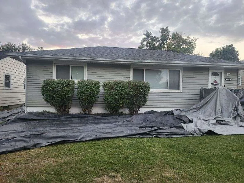 Front exterior of a residential home in Cedar Rapids, IA with a completed roof replacement and protective tarps in place.